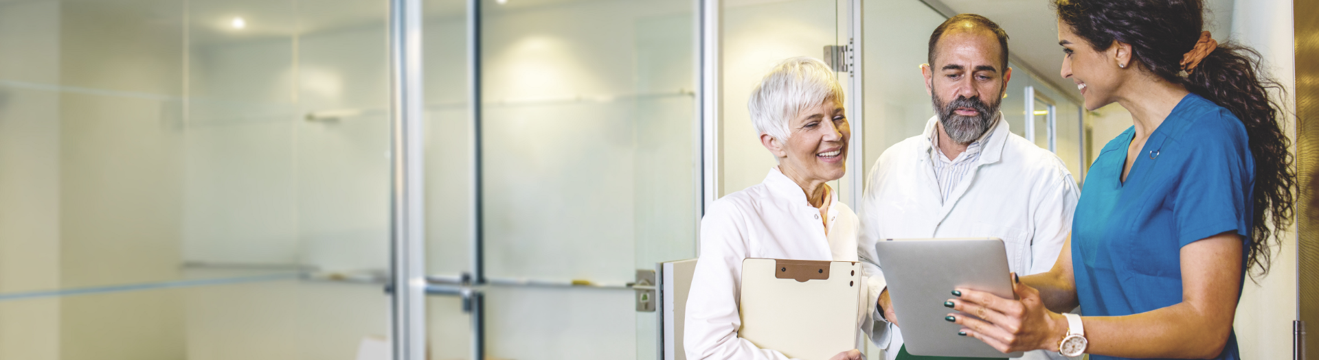 A nurse shows a folder to two doctors, one smiles holding another, as they review info at a specialist center.