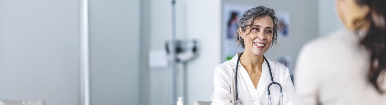 Smiling female doctor in clinic room, consulting a patient, representing resources for healthcare providers.